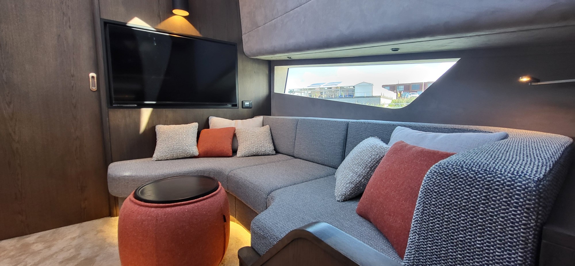 Loungehoek met tv en kleurrijke kussens benedendeks in de Steeler Enigma 50