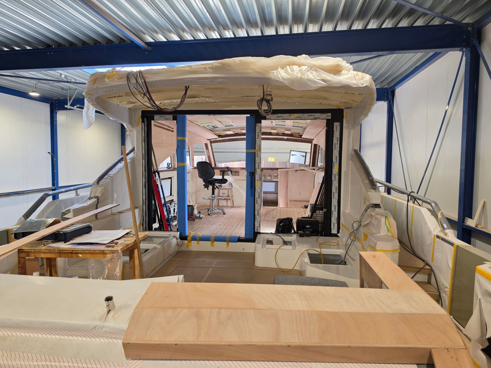 Kuip van een jacht in afbouw met zicht op de salon door de schuifpui