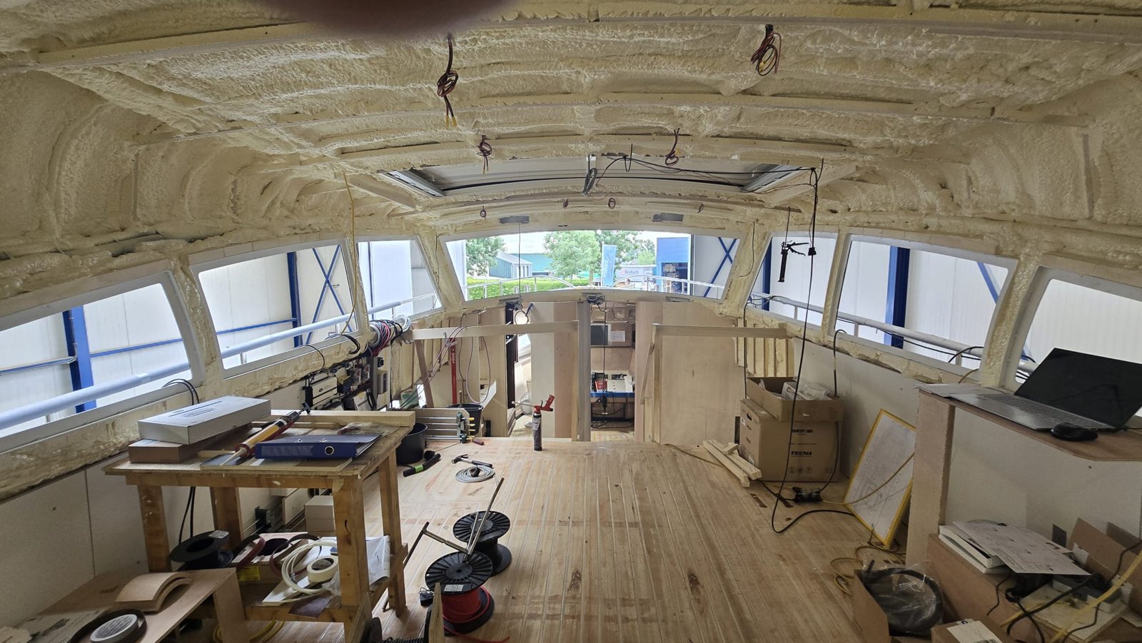 Stuurhuis in aanbouw met gespoten isolatie tegen het dak en een werkbank